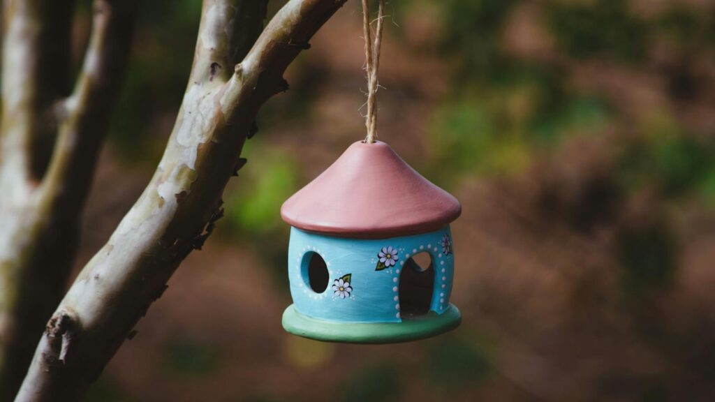 Vibrant ceramic calay birdhouse suspended on a tree branch