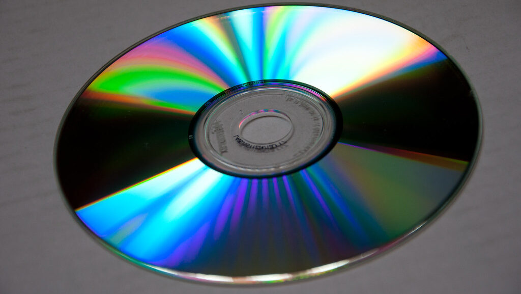 Shiny CD lying flat on clean white surface