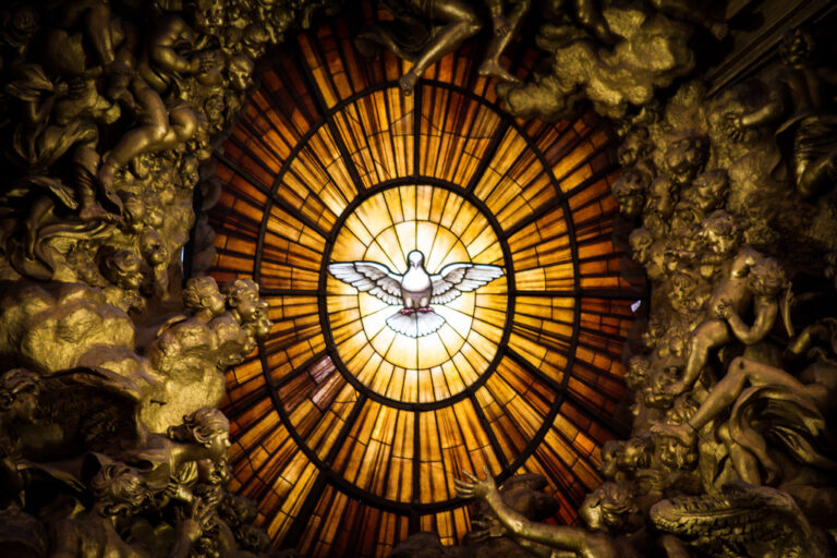 A stained glass window depicts a white dove radiating light, surrounded by gilded sculptures.