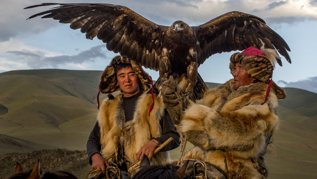 Two traditional Mongolian eagle hunters with a trained Golden Eagle