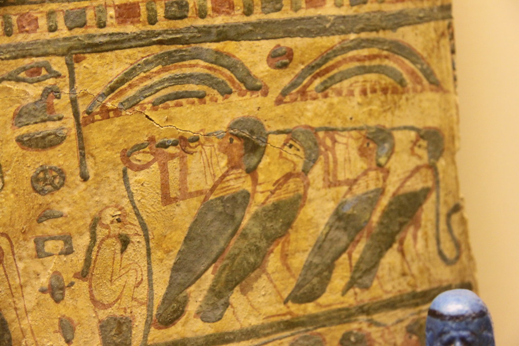 An ancient Egyptian painting shows figures on a cracked and aged surface.