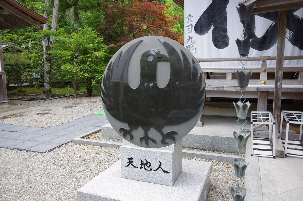A large, circular dark stone carving depicts a stylized bird with outstretched wings.