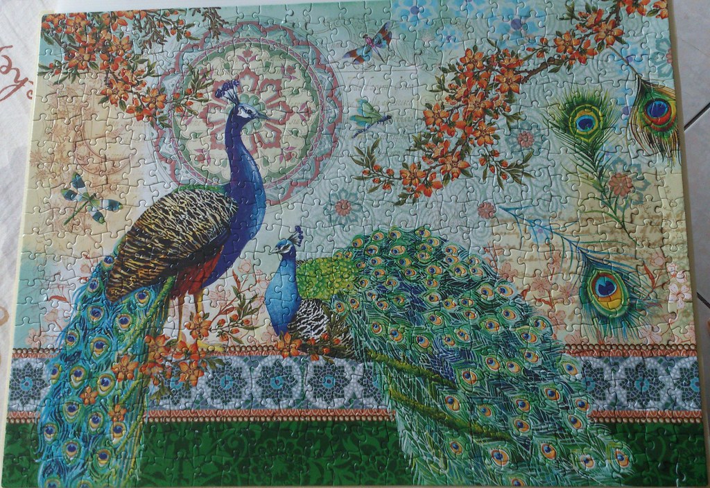 A vibrant puzzle shows two peacocks with their elaborate tail feathers spread out.