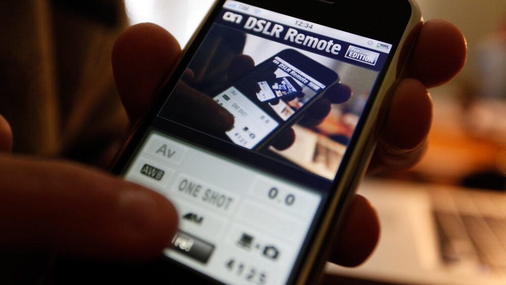 Person displaying smartphone screen with camera remote control app