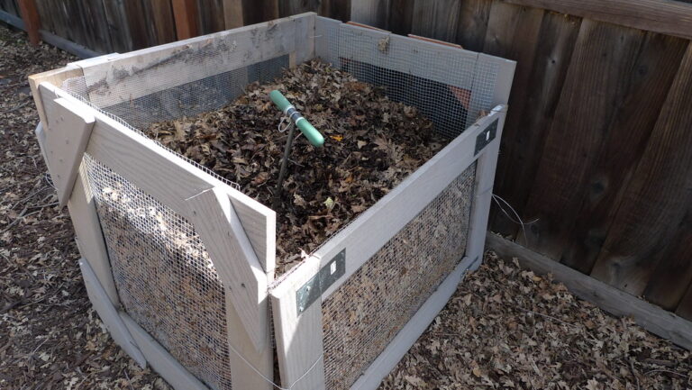 Wooden compost box filled with leaves