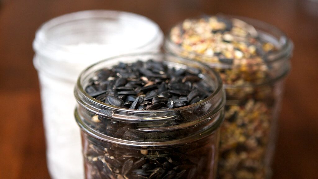 Three glass jars filled with different types of seeds