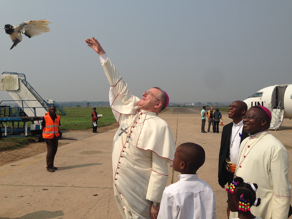 A religious leader releases a dove, which flies upward into the sky.