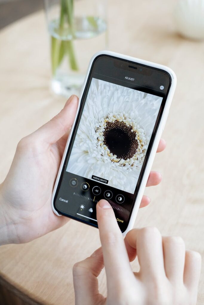 Hands using a smartphone to edit a white flower image