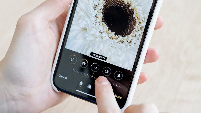 Hands using a smartphone to edit a white flower image