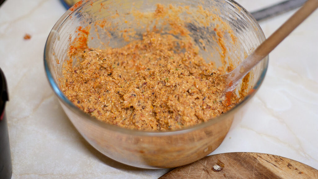 Hand stirring bird suet mixture in bowl using wooden spoon