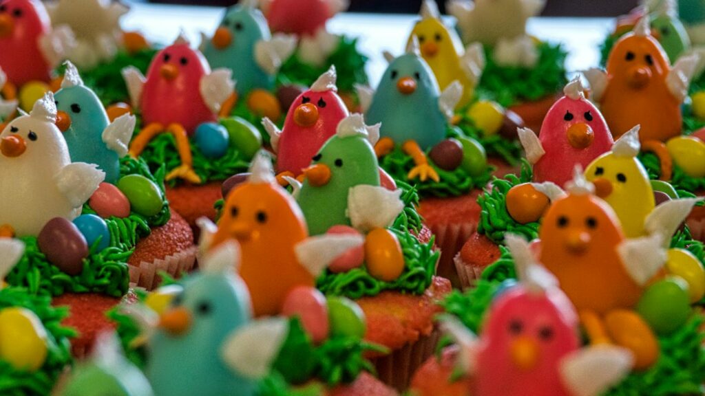 Cupcakes topped with multicolored bird decorations for a themed party