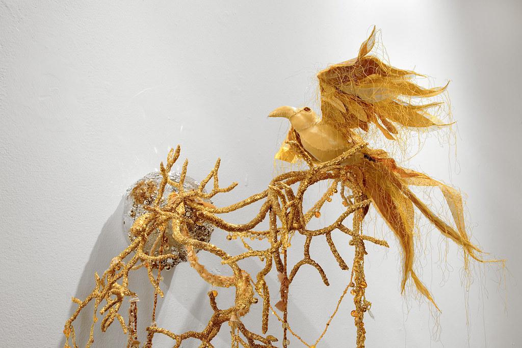An elaborate art sculpture features a golden bird perched on twisted, branch-like forms.
