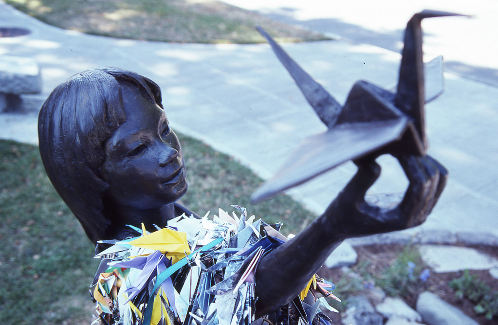 A bronze statue of Sadako Sasaki holds up a large origami crane.