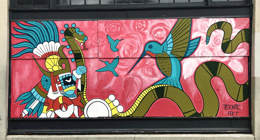 This vibrant mural features a hummingbird alongside a feathered serpent and other symbolic elements.