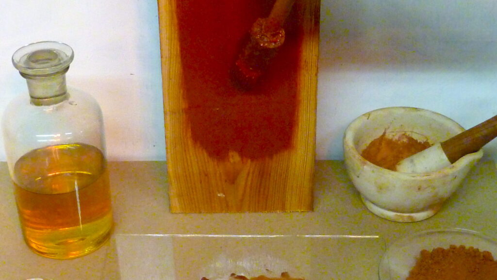 Hand applying linseed oil to wooden surface using a paintbrush