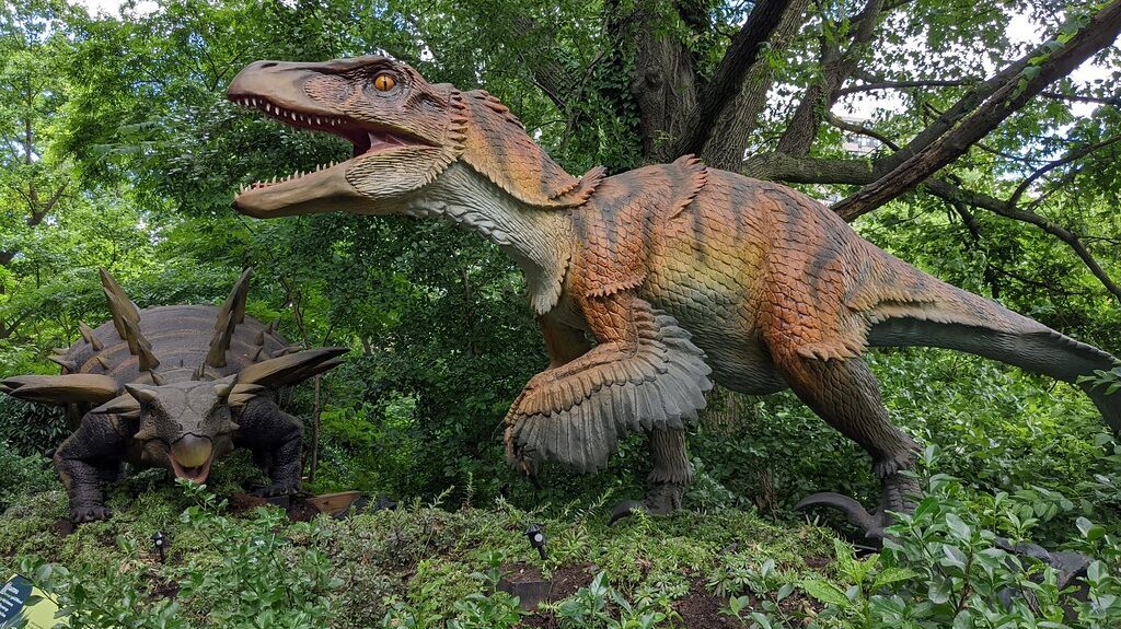 Utahraptor model exhibit nestled among lush green vegetation