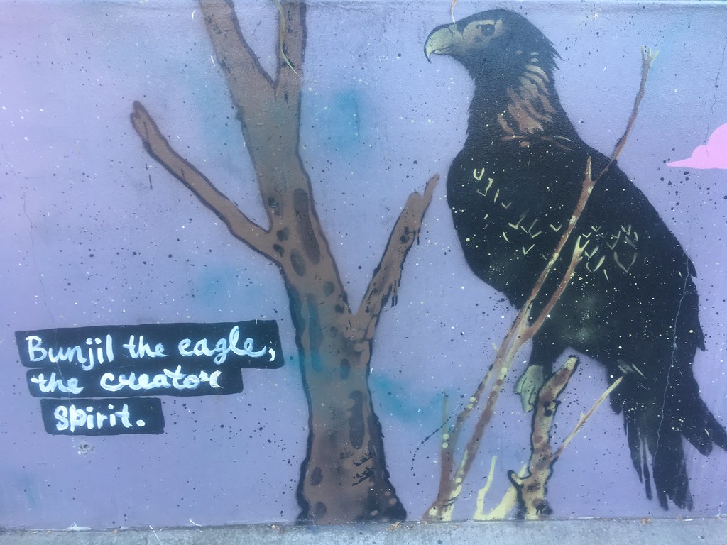 A vibrant mural depicts a large black eagle perched on a tree branch, with text below it.