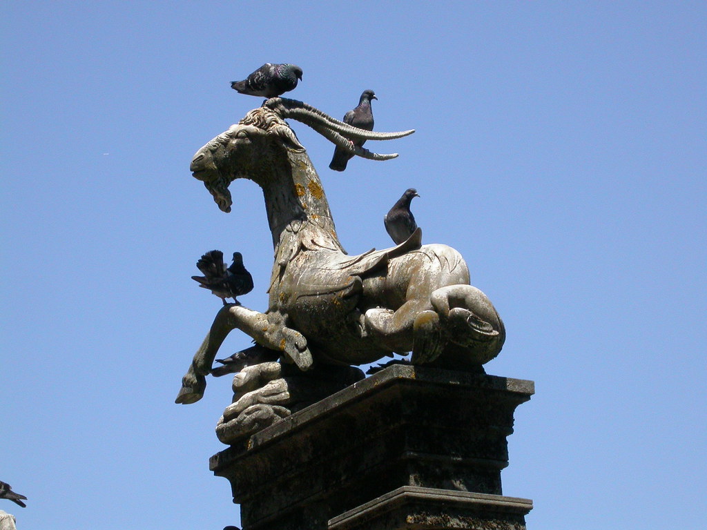 A bronze sculpture of a mythical creature is adorned with several pigeons.