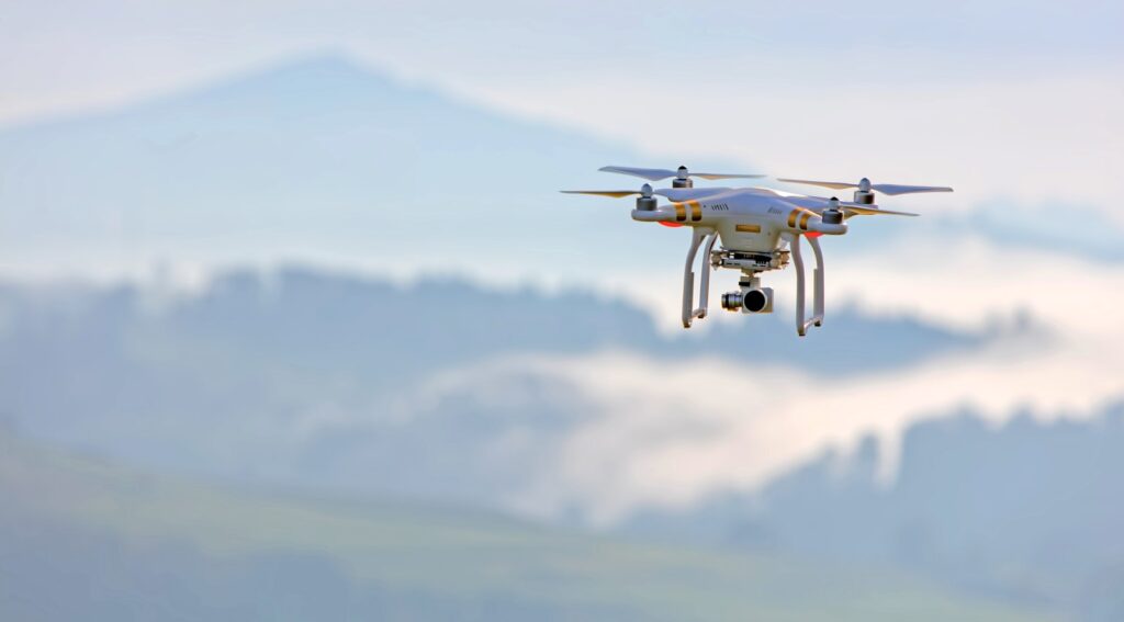 Drone flying in the sky with forested mountains in the background