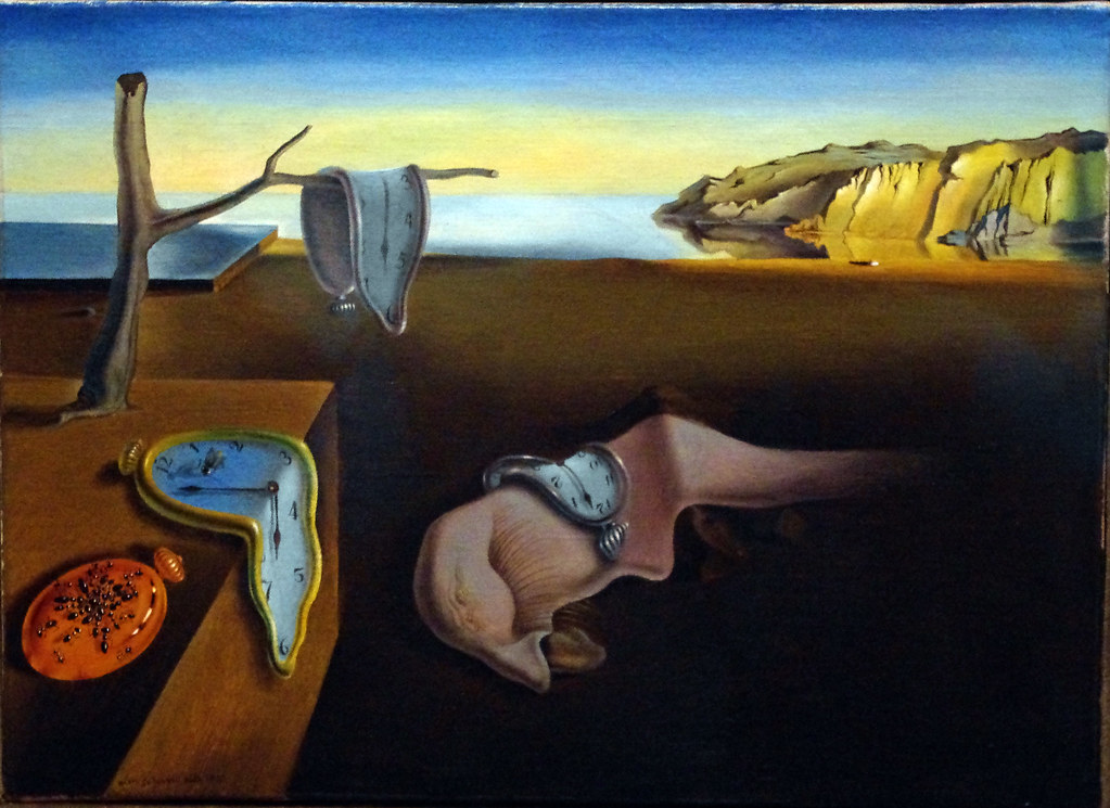 A surreal painting depicts melting clocks in a desolate landscape with a still body of water and cliffs.
