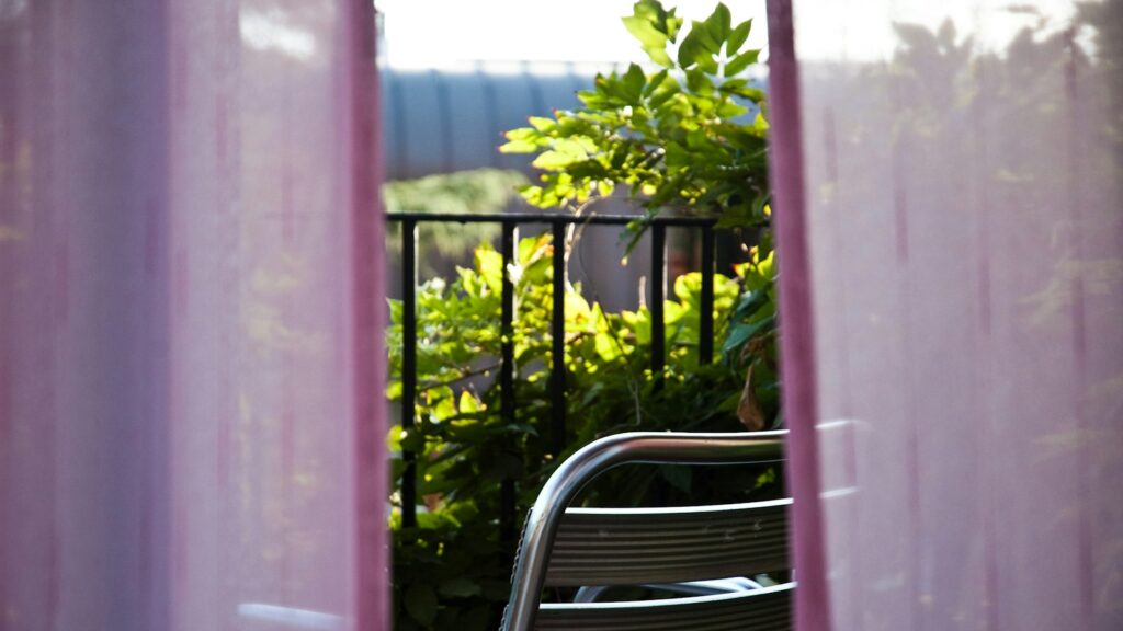 Balcony featuring a chair partially hidden behind flowing pink curtains