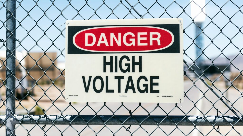 High voltage warning sign on metal fence