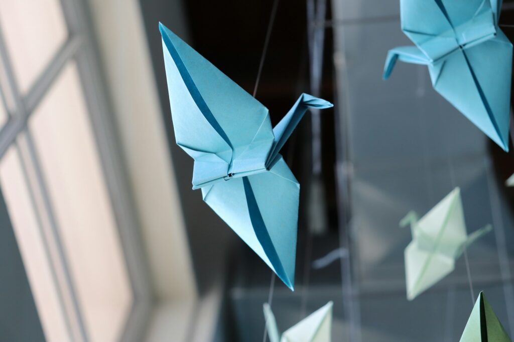 Light blue origami cranes are suspended, creating a peaceful display.