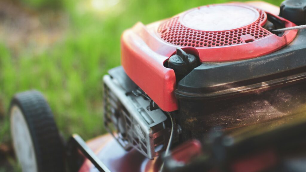 Close up of a red lawnmower on a backyard garden