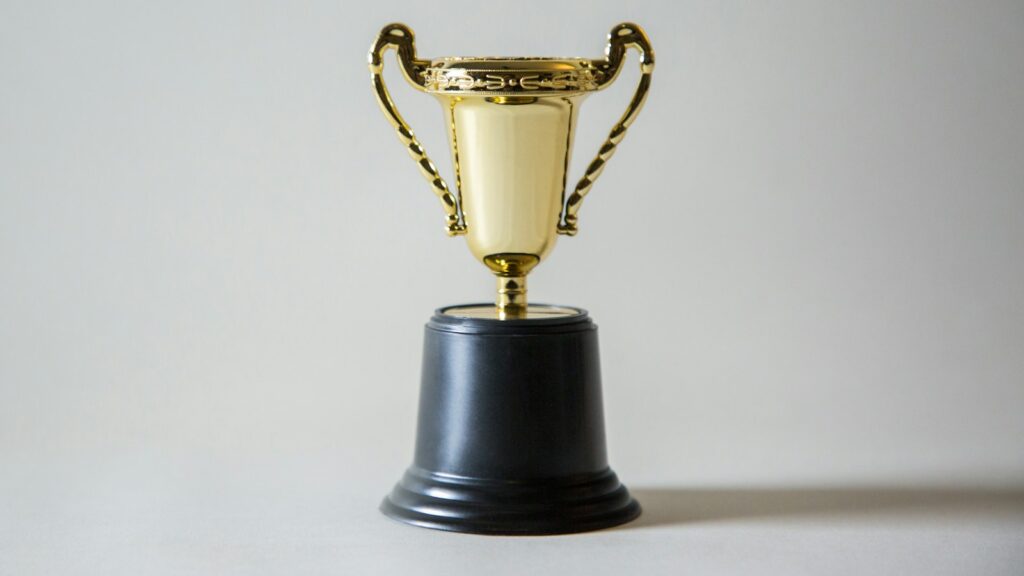 Shiny award trophy placed on white tabletop 