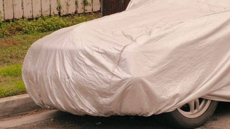 Parked car fully covered with protective car cover